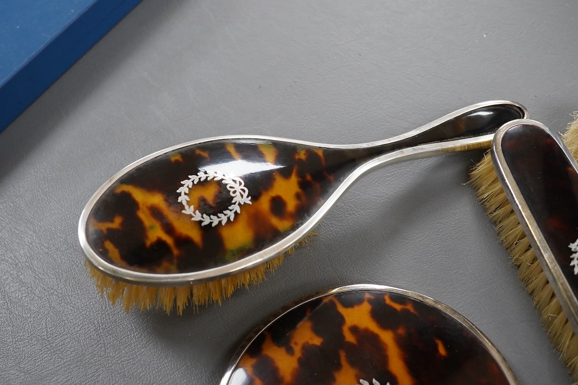 A matched George V silver and tortoiseshell mounted four piece mirror and brush set, Birmingham, 1927/8/9, mirror 22.7cm.